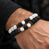 Man wearing a SEYOR two-piece bracelet set made with matte black lava stones, white howlite beads and dark metallic spacers.