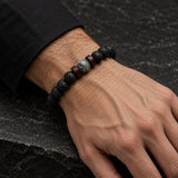 Man wearing a SEYOR black lava stone bead bracelet with grey stone center beads and dark wooden spacers