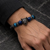 Man wearing a SEYOR black lava stone bracelet with blue tiger eye beads and a gunmetal wolf head centerpiece