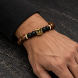 Man wearing a SEYOR brown wood and matte black bead bracelet with a gold owl charm and crystal accents