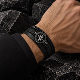 Man wearing a SEYOR multilayer black leather bracelet with braided strands, silver-tone compass medallion and magnetic clasp.