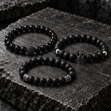 Three SEYOR men’s black beaded bracelets with polished beads, matte beads, a black crown charm and gunmetal spacer details on dark stone.