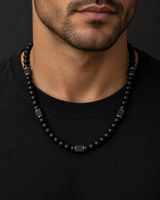 Male model wearing a matte black onyx bead necklace with square lava stone accents and gold-tone spacers.