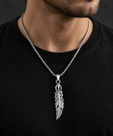 Male model wearing an ornate silver-tone feather pendant necklace with a black T-shirt.