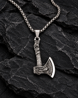 Engraved silver-tone Viking axe pendant necklace displayed on rugged black stone.