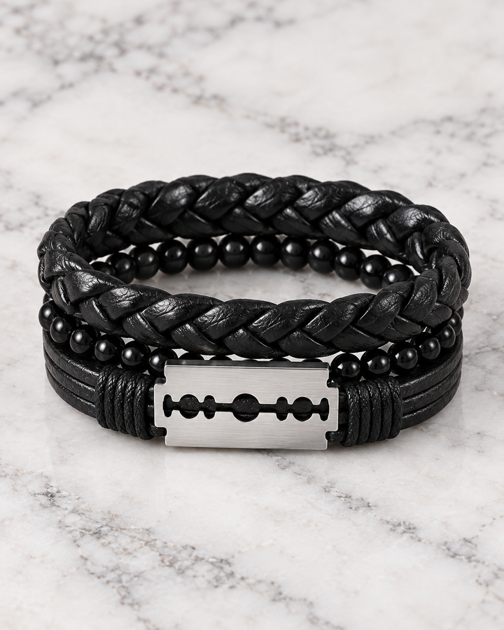 Front view of a men’s black layered bracelet set featuring a silver-tone razor blade centerpiece