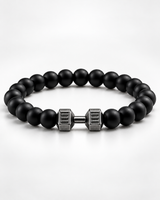 A beaded bracelet with matte black round beads and a central metallic clasp shaped like a stylized dumbbell, shown on a clean light gray background.